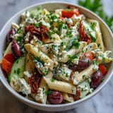 Colorful Greek pasta salad with briny olives, crisp veggies, and creamy feta, tossed in herb dressing.