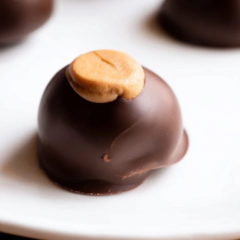 Perfectly round buckeyes, partially coated in glossy chocolate, offer a delicious, bite-sized treat visually.