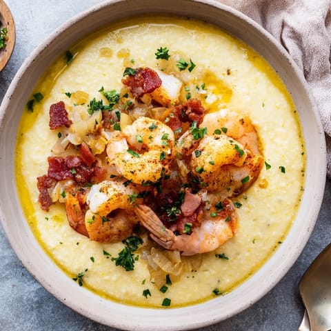 Spoonful of Southern Shrimp and Grits featuring tender Cajun shrimp and cheesy grits served steaming hot in a rustic bowl.