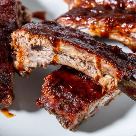 Freshly grilled BBQ Ribs glistening with sticky glaze, served alongside creamy coleslaw on a wooden board.