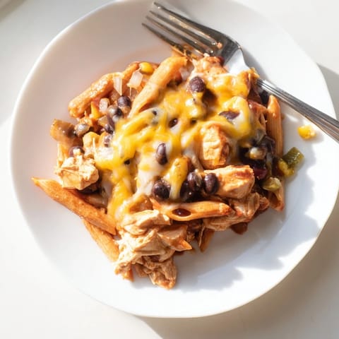 A skillet of Chicken Enchilada Pasta, topped with melted cheddar and Monterey Jack, garnished with fresh cilantro.