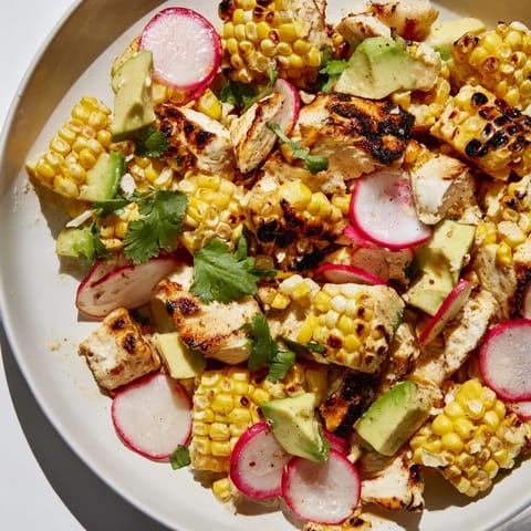 Savory grilled chicken and smoky roasted corn top a vibrant chopped salad with avocado and radishes, dressed in a glistening lime vinaigrette.  