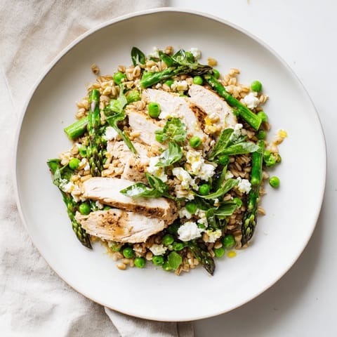 Warm Spring Farro Chicken Salad features tender grains, grilled chicken, crisp asparagus, peas, and arugula tossed in a bright lemon vinaigrette.