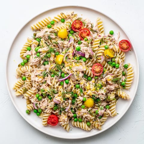 Freshly tossed Lemony Tuna Pasta Salad served in a white bowl, garnished with lemon zest and dill.
