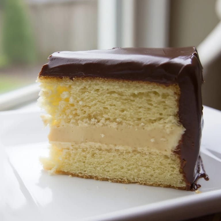 A perfectly sliced Ho Ho Cake exhibits layers of yellow cake, vanilla cream, and chocolate ganache.