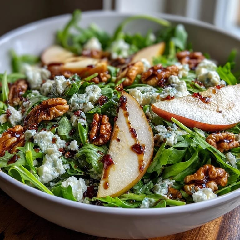 A close-up of the vibrant Arugula and Pear Bowl drizzled with balsamic dressing on a rustic wooden table.